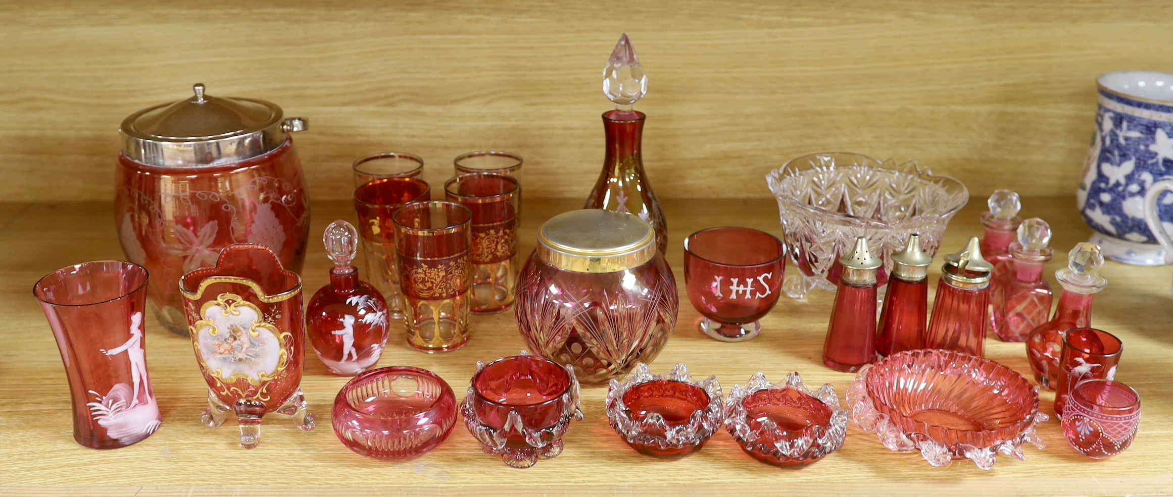 Antique and later cranberry glassware including a biscuit barrel etched with grapevines, Mary Gregory beakers and scent bottle and a vase with enamelled and gilt decoration, the largest 21cm high